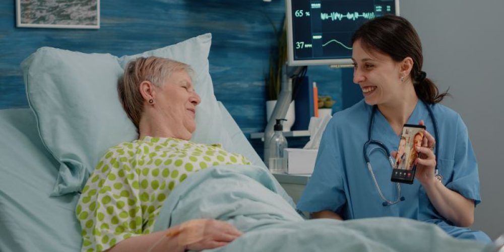 senior-woman-talking-family-video-call-communication-nursing-home-nurse-holding-smartphone-with-online-remote-conference-patient-bed-with-disease-giving-assistance (1)